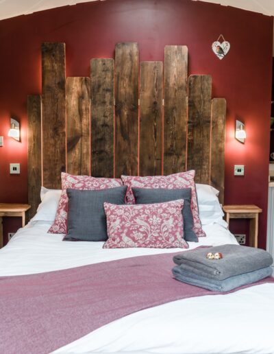 Inside a roundhouse, back lit reclaimed timber head board of king sized bed
